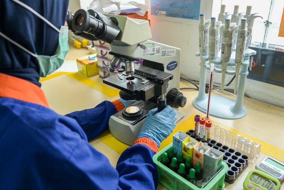 Technician in lab coat examining samples using a microscope in a modern laboratory setting.